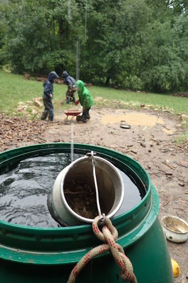 Kinder mit Regenkleidung spielen am Matschplatz