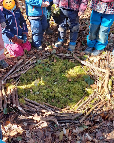 Kinder stehen um ein selbstgebautes Nest aus Ästen und Zweigen.