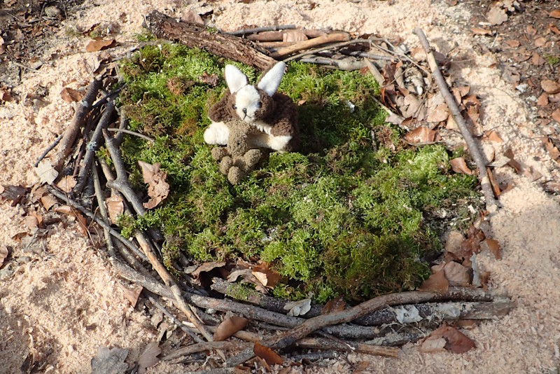 Stoffosterhase im Naturnest aus Zweigen und Moos