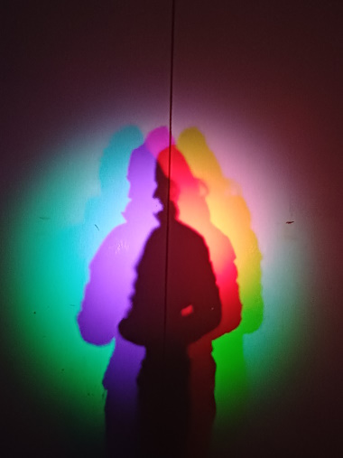 Farbige, leicht versetzte Schatten, die von Eva stammen werden auf einer Wand sichtbar