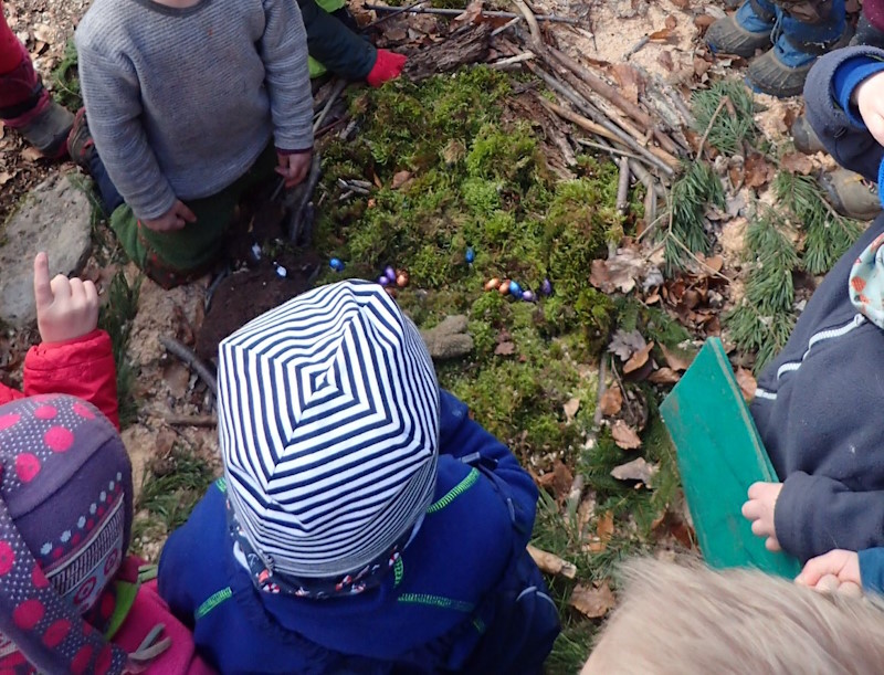 Kinder finden kleine Ostereier im Moos